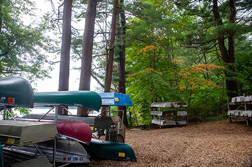 boats and canoes on a rack in front of Shenpsit lake 