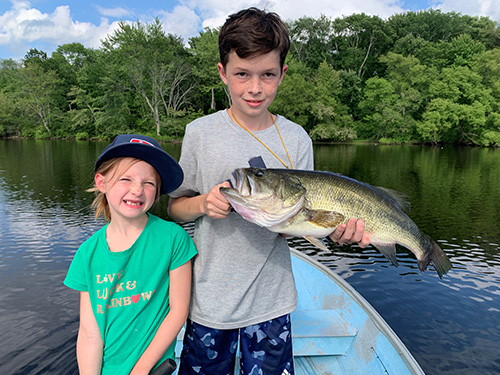 two children fishing at a lake with one of them holding a big fish